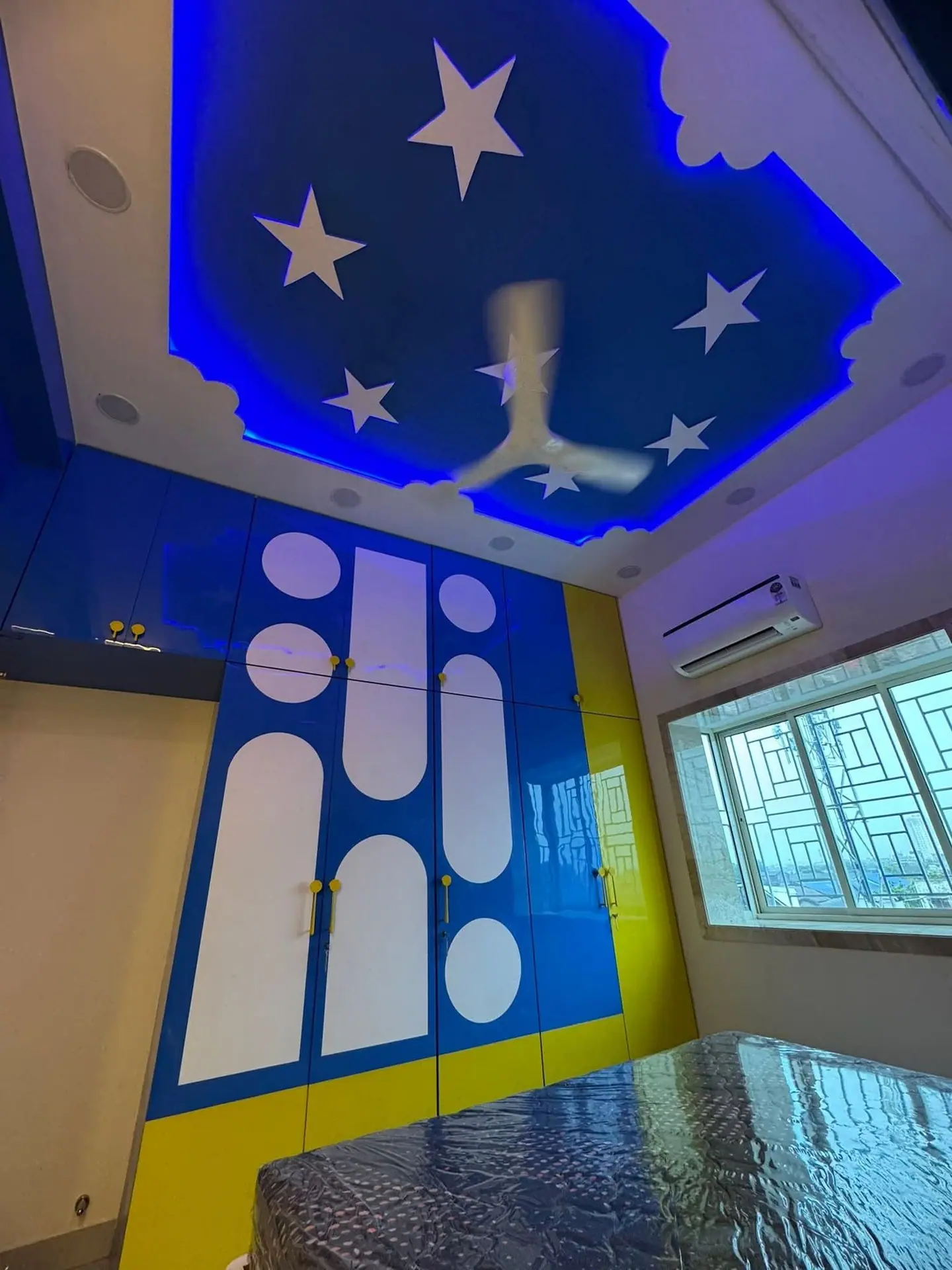 Children's room false ceiling with a blue star-cut cove above matching wardrobes