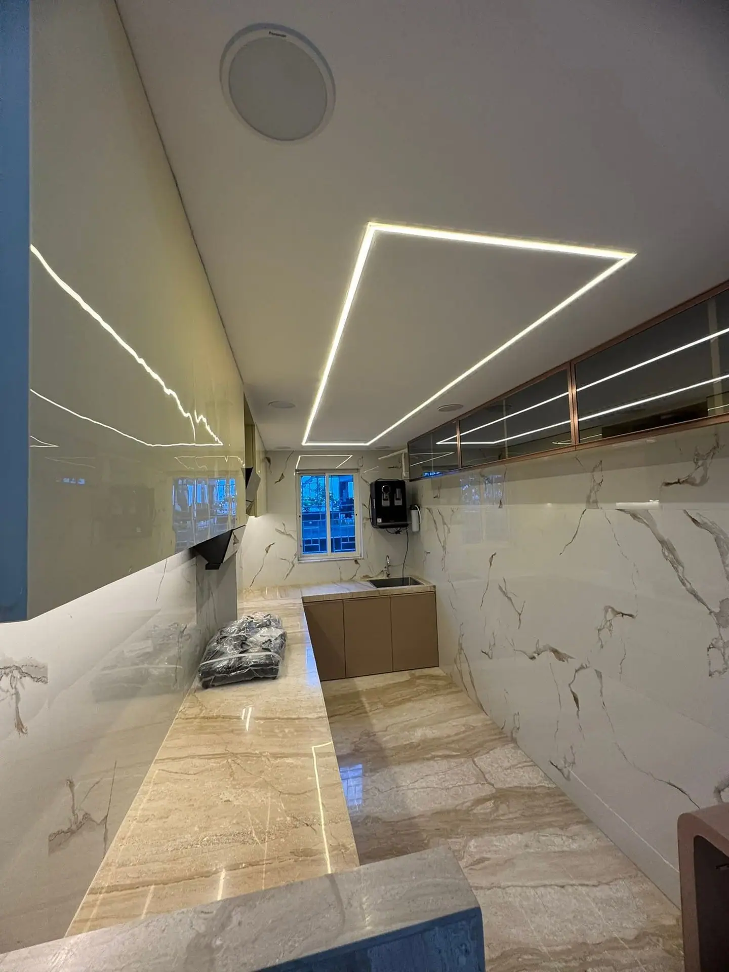 Modular kitchen with high-gloss cabinets, a marble-effect wall and linear ceiling lights